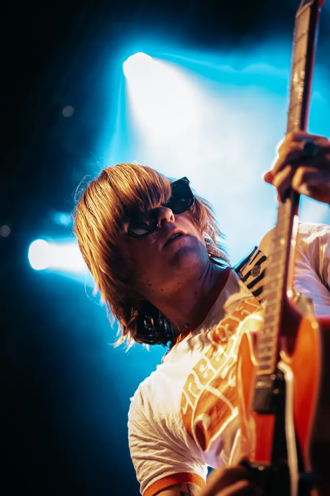 Guitarist on stage in sunglasses, lit by blue spotlights